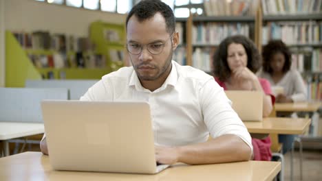 Hombre-Afroamericano-Enfocado-Que-Usa-Una-Computadora-Portátil-En-La-Biblioteca