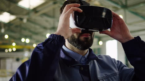 Close-up-view-of-Caucasian-man-putting-on-VR-glasses-in-a-big-factory