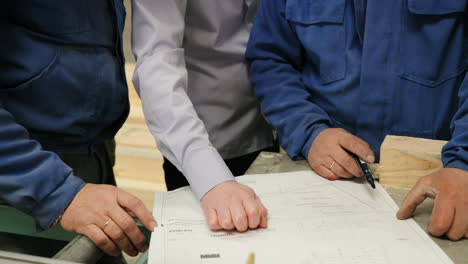 Close-up-view-of-male-hands-on-blueprint-in-a-factory
