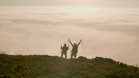 Senior-couple-standing-on-top-of-mountain-and-raising-arms-up
