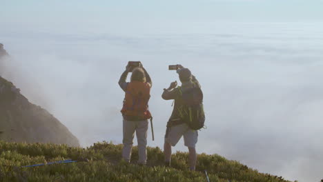 Senior-couple-standing-on-top-of-hill-and-taking-photo-on-phone