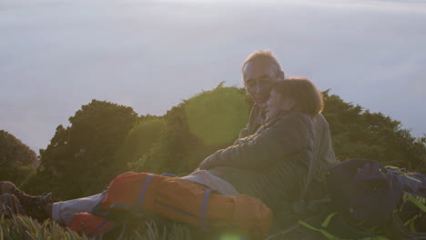 Senior-couple-lying-on-mountain,-kissing-and-enjoying-view