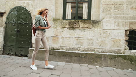 Caucasian-blonde-young-woman-walking-down-the-street-while-jumping-and-listening-to-music