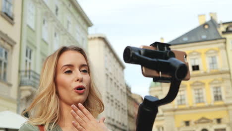 Nahaufnahme-Einer-Kaukasischen-Blonden-Jungen-Frau,-Die-Ein-Video-Auf-Dem-Smartphone-Aufnimmt,-Während-Sie-Es-Mit-Einem-Selfie-Stick-Auf-Der-Straße-Hält
