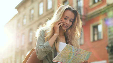 Bottom-view-of-blonde-young-woman-talking-on-the-phone-while-walking-the-city-holding-a-map