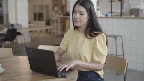 Positive-young-female-entrepreneur-using-laptop