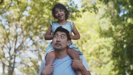 Happy-young-Asian-man-giving-his-cheerful-daughter-piggyback-ride
