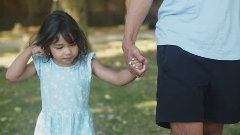 Smiling-cute-Asian-girl-walking-with-father-holding-his-hand