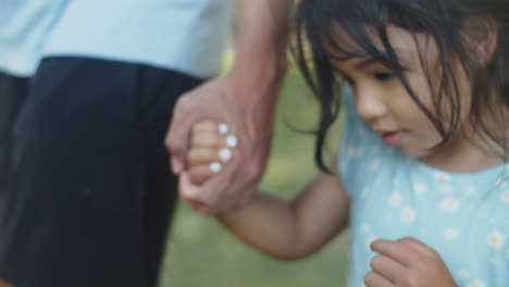 Close-up-of-cute-Asian-girl-walking-with-father-holding-his-hand