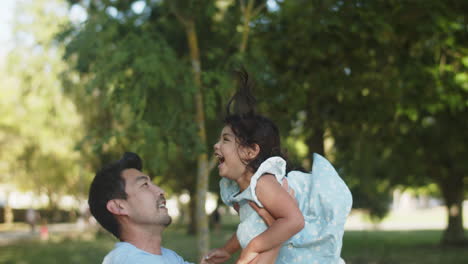 Happy-Asian-father-tossing-up-little-daughter-outdoors