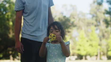 Süßes-Asiatisches-Kleines-Mädchen,-Das-Seifenblasen-Mit-Vater-Im-Park-Bläst