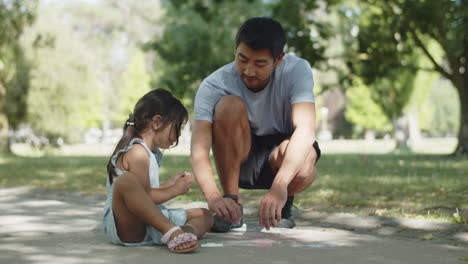 Happy-father-drawing-heart-on-hand-of-his-daughter-with-chalk