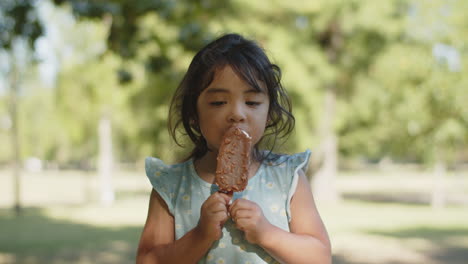 Portrait-of-cute-little-Asian-girl-eating-chocolate-ice-cream-at-the-park