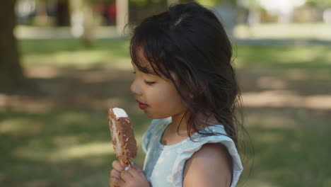 Side-view-of-cute-little-girl-licking-chocolate-ice-cream-outdoors