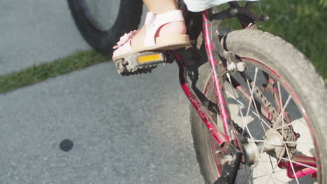Close-up-of-little-girl-spinning-pedals-of-bicycle