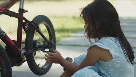 Curious-little-girl-looking-at-spinning-pedals-of-her-bike