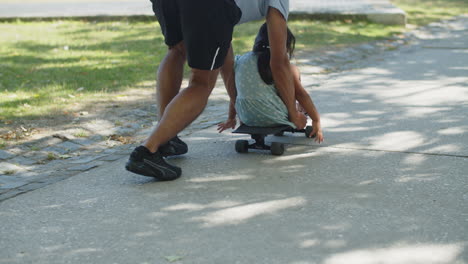 Rear-view-of-young-man-pushing-skateboard-with-little-girl-on-it