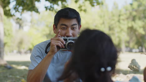 Smiling-Asian-man-taking-photo-of-little-daughter-with-camera