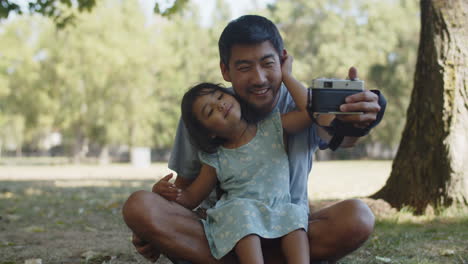 Happy-Asian-father-taking-selfie-with-daughter-with-camera