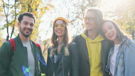 Two-happy-Caucasian-young-couples-of-friends-smiling-to-the-camera-in-the-park-in-autumn