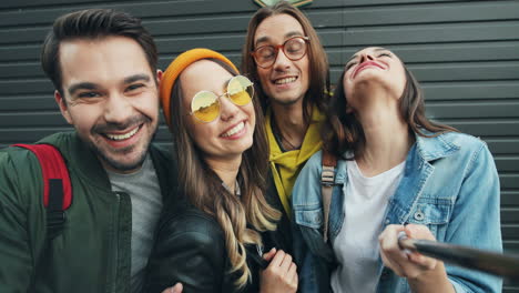 Close-up-view-of-group-of-caucasian-funnt-friends-in-hipster-style-smiling-and-posing-while-taking-selfies-in-the-street