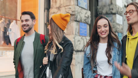 Portrait-shot-of-caucasian-young-group-of-friends-walking-down-the-street-while-talking-and-laughing-in-the-city