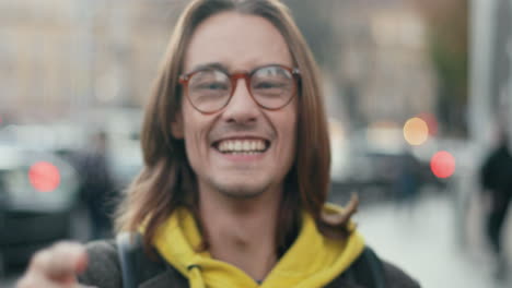 Close-up-view-of-young-cheerful-hipster-guy-in-glasses-making-different-funny-faces-and-grimacing-to-the-camera-in-the-street