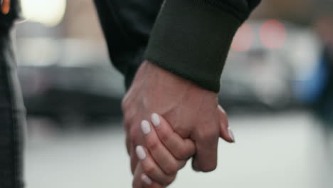 Close-up-view-of-Caucasian-hands-of-man-and-woman-holding-each-other-as-they-walk-down-the-street