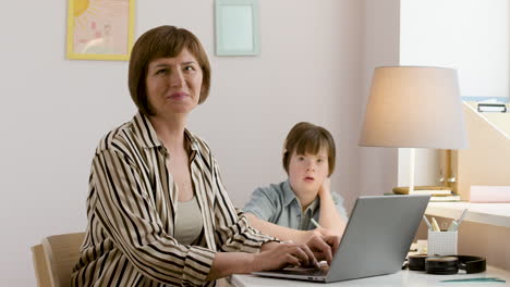 Working-mom-using-laptop-next-to-her-focused-daughter