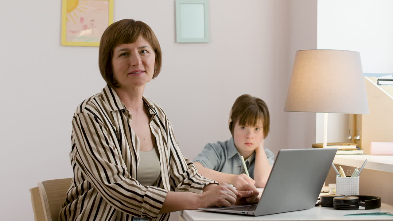 Free stock video - Woman looking at camera while her daughter studies