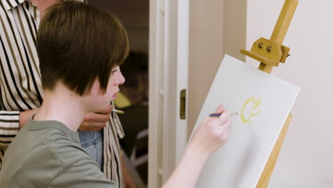 Young-girl-with-down-syndrome-paints-a-sun-on-a-canvas
