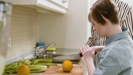 Mother-and-daughter-cutting-an-orange-in-the-kitchen
