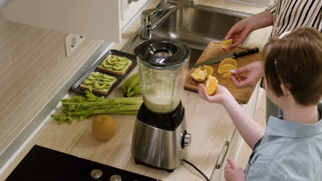 Mother-and-her-daughter-cutting-fruits-and-putting-inside-a-blender-to-do-smoothie