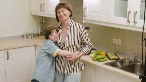 Happy-mom-and-daughter-smiling-and-hugging-in-the-kitchen