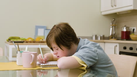 Young-girl-writing-on-paper-in-the-kitchen