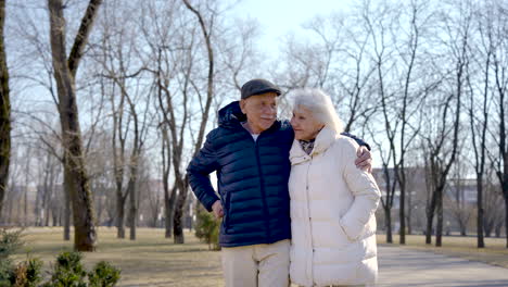 Senior-couple-holding-hands,-walking-and-hugging-in-the-park-on-a-winter-day