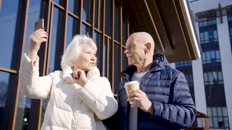 Senior-couple-making-a-selfie-with-smartphone-in-the-street-on-a-winter-day