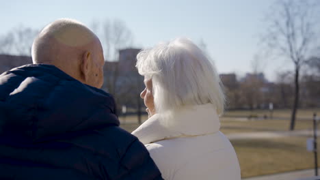 Rear-view-of-a-senior-couple-hugging-and-talking-in-the-park-on-a-winter-day