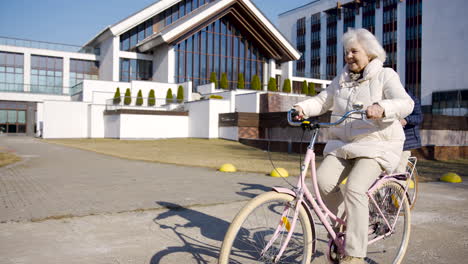 Senior-woman-riding-a-bike-in-the-street-on-a-winter-day