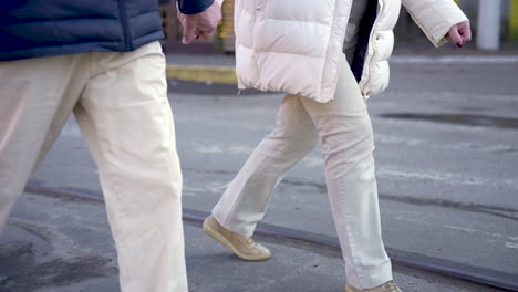 Side-view-of-a-senior-couple-holding-hands-and-walking-down-the-street-on-a-winter-day