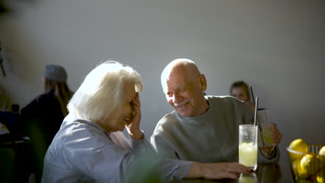 Seitenansicht-Eines-älteren-Paares,-Das-Limonade-Trinkt-Und-Sich-Unterhält,-Während-Sie-Bei-Sonnenuntergang-In-Einer-Bar-Sitzen