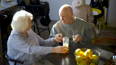 Blick-Von-Oben-Auf-Ein-älteres-Paar,-Das-Limonade-Trinkt-Und-Sich-Unterhält,-Während-Sie-Bei-Sonnenuntergang-In-Einer-Bar-Sitzen