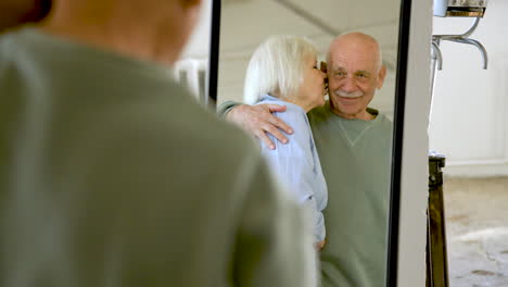 Senior-couple-hugging-and-looking-in-the-mirror-in-a-studio