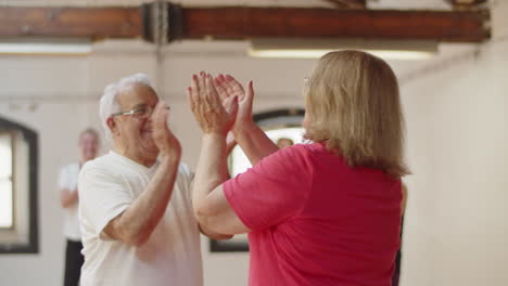 Medium-shot-of-senior-couple-dancing-waltz-in-ballroom-and-clapping-with-the-whole-group