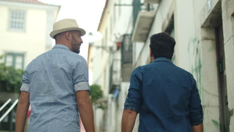 Back-view-of-male-gay-couple-walking-around-city-and-talking