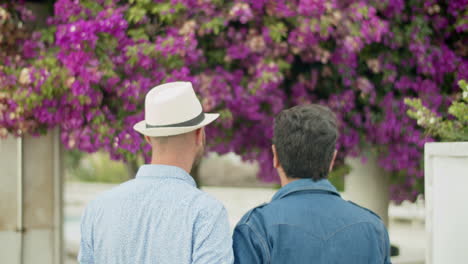 Back-view-of-homosexual-men-going-to-garden-with-lilac-trees
