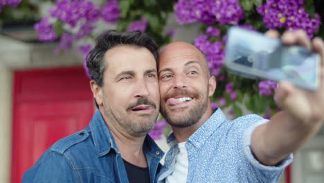 Happy-gay-couple-taking-selfie-in-street-and-making-grimaces