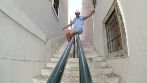 Long-shot-of-man-sliding-down-railing-of-stairs-in-narrow-street