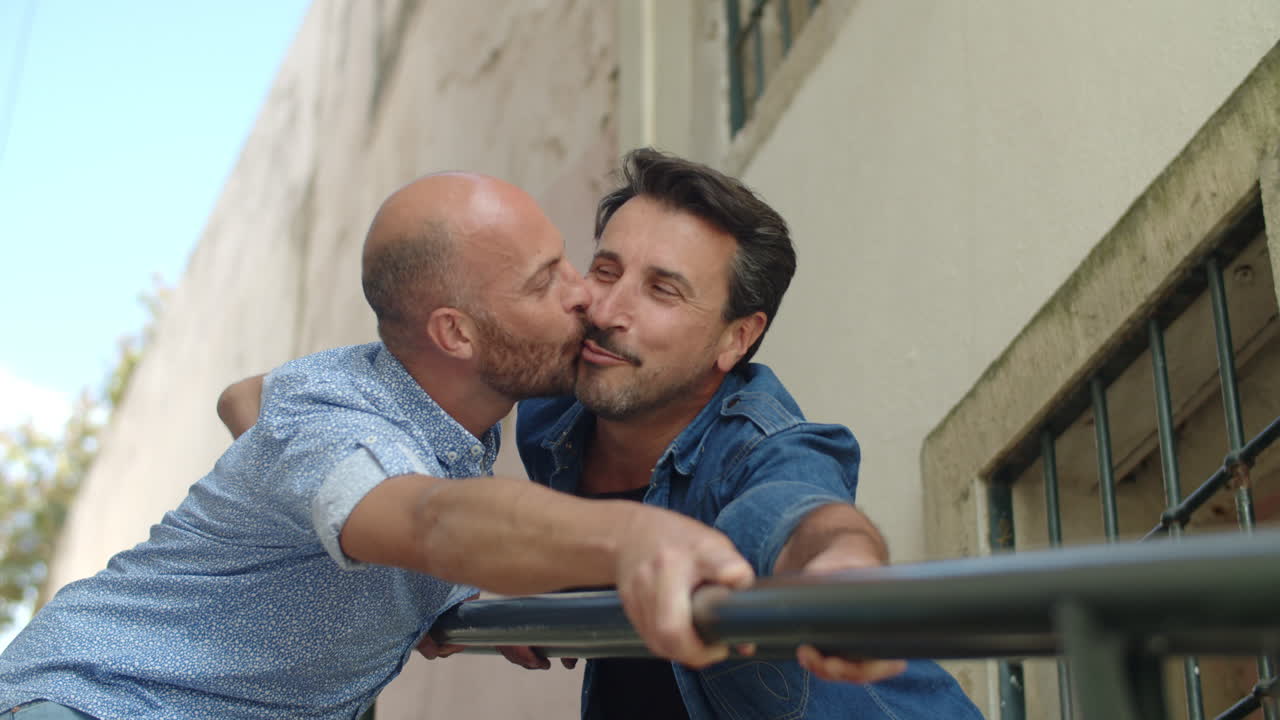 Стоковое видео категории «Бесплатно» — Счастливые геи целуются и держатся за перила лестницы