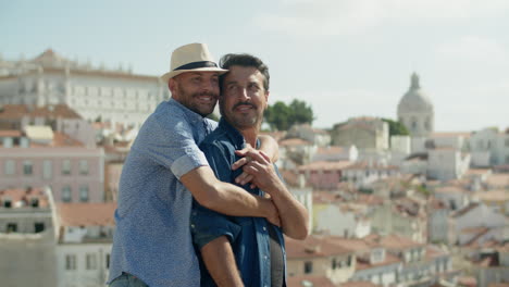 Medium-shot-of-cheerful-gay-man-hugging-his-boyfriend-from-back-with-amazing-landscape